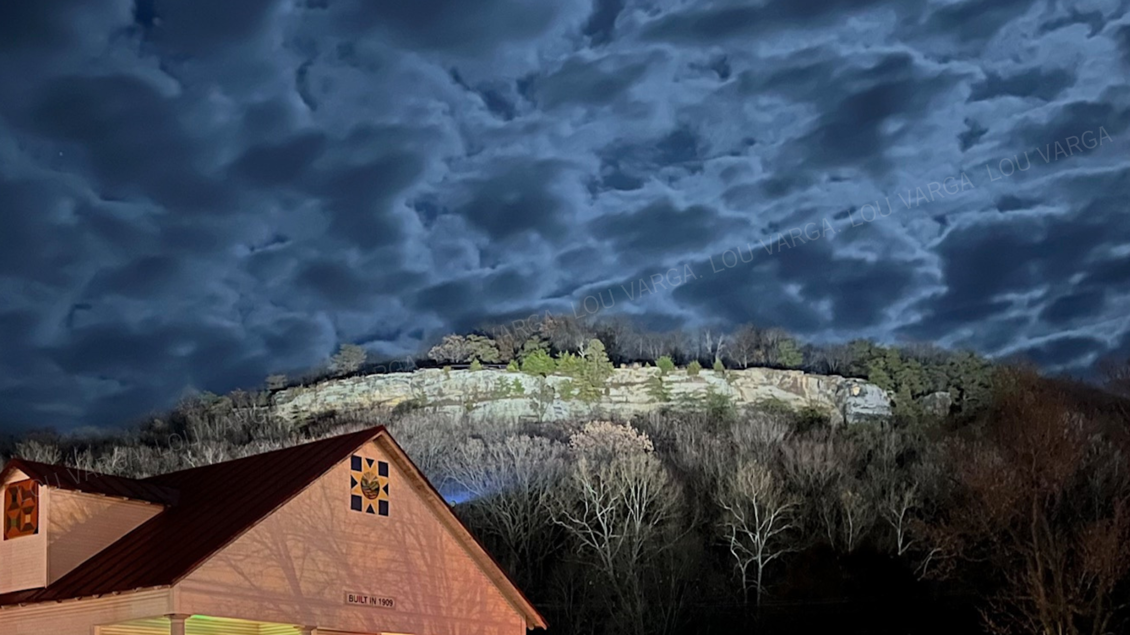 A moonlit bluff rising over a historic 1909 barn — the Ohio landscape at the heart of Lou Varga's writing